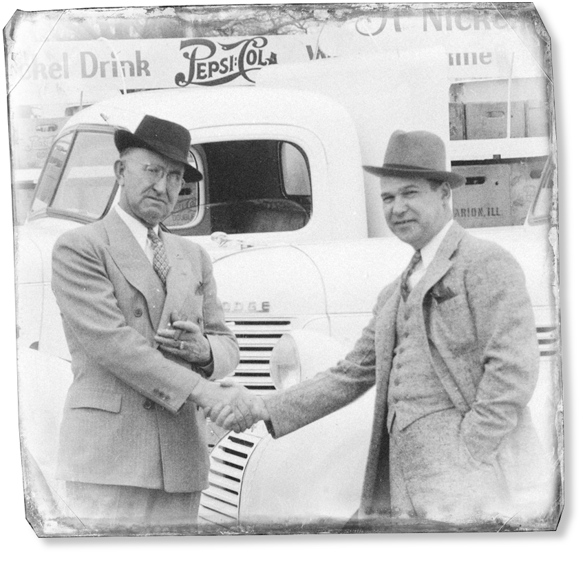 vintage picture of two men shaking hands wearing suits in front of pepsi delivery trucks