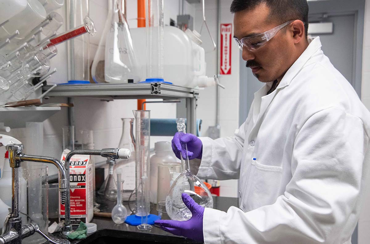 man in lab coat holding a glass beaker