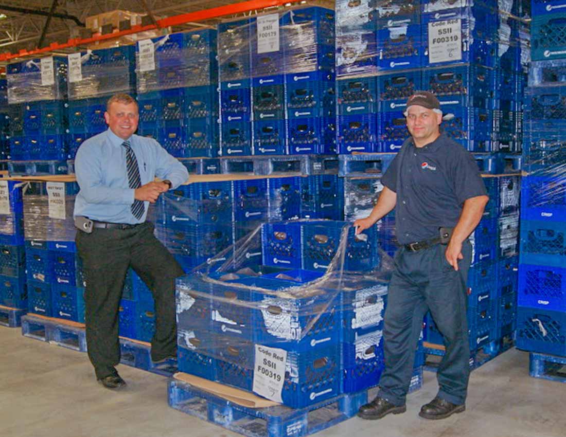 two employees posing next to pallet